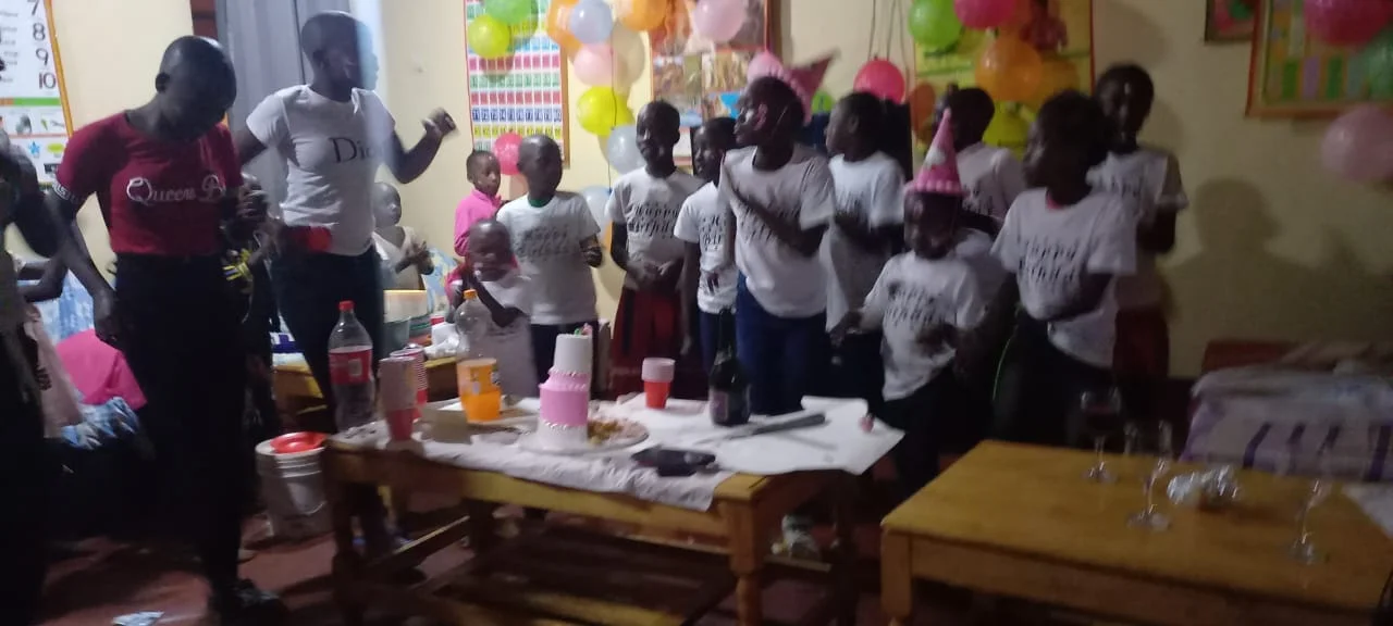 Children and adults gathered around a table during a Restoration celebration